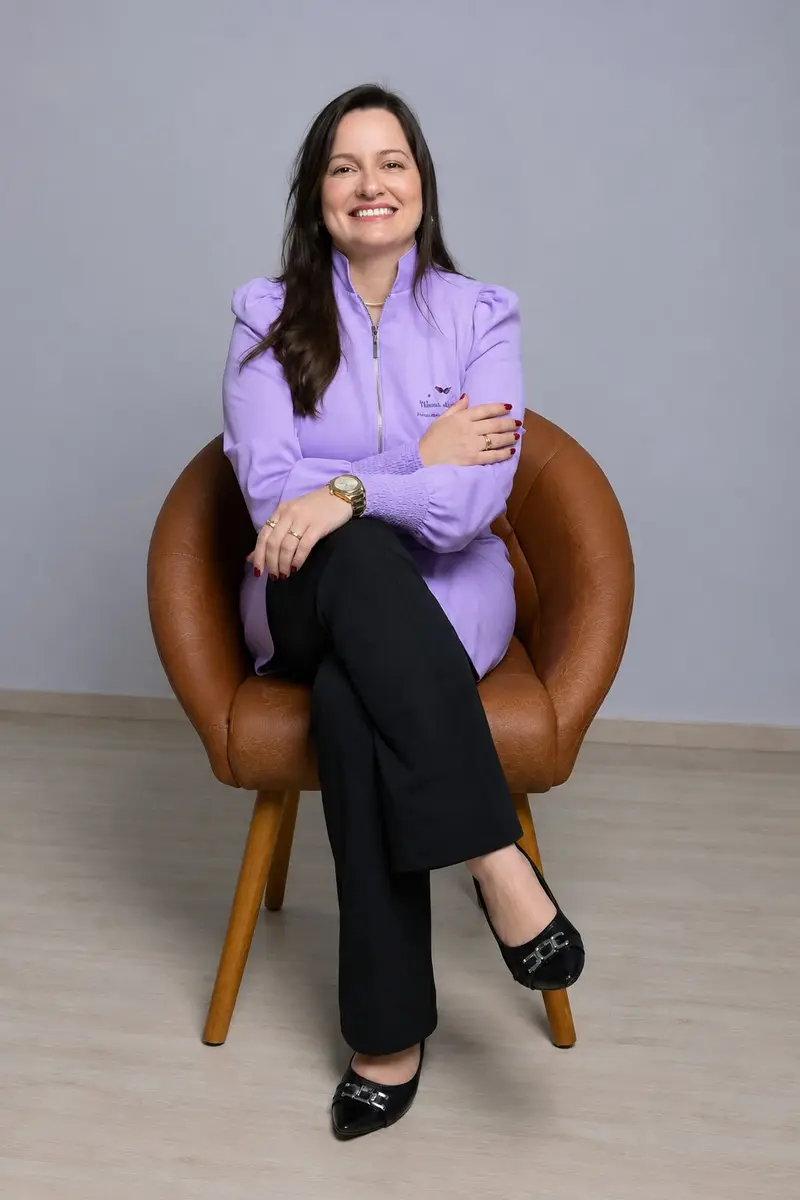 Viviane Nepomuceno sentada em uma poltrona de couro, de blusa lilás, sorrindo